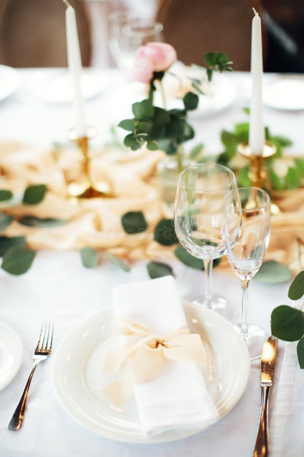Festive table setting in gentle pastel colors. Plate and glasses close up. Gala dinner in honor of birthday or wedding.