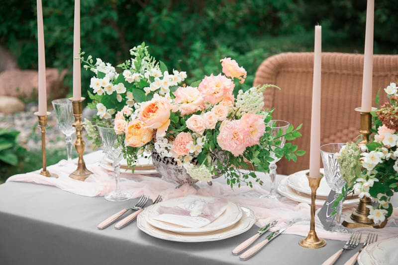 A festive wedding table with candles, glasses, decorated with flowers. The decor is made in orange and green tones. Close up. On