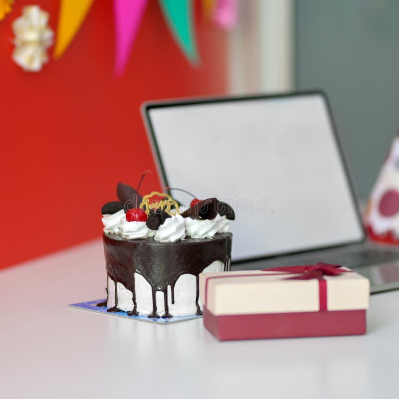 Festività di compleanno online con panna per notebook e scatola regalo in bianco schermo immagine stock libera da diritti