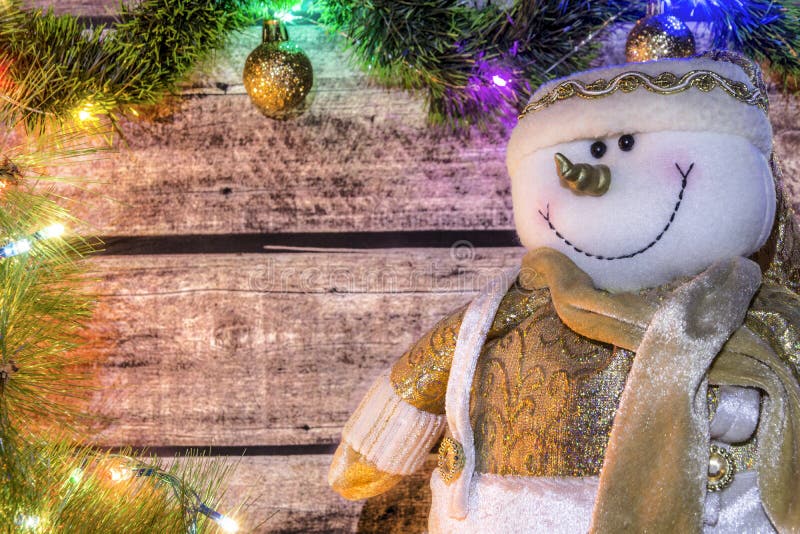 Festlig julbakgrund av mörka gamla träbräden, gran-trädet, snögubben och den lysande girlanden med kulöra ljus och jul b royaltyfri fotografi Festlig julbakgrund av mörka gamla träbräden, gran-trädet, snögubben och den lysande girlanden med kulöra ljus och jul b royaltyfri fotografi
