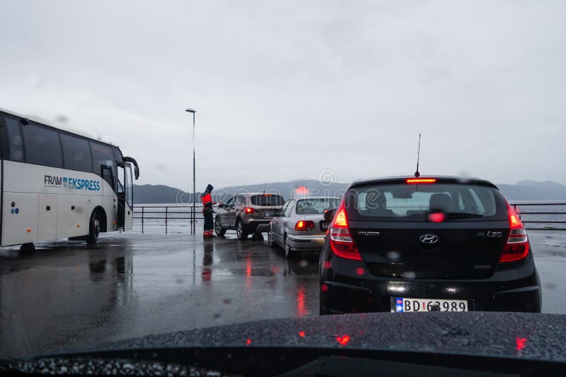 Editorial 09.06.2019 Festøy Ferryport Norway One of the crew members sells tickets in the rain to car drivers. Editorial 09.06.2019 Festøy Ferryport Norway One of the crew members sells tickets in the rain to car drivers