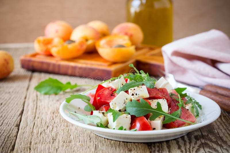 Feta-arugulasalade met tomaten op witte plaat, de zomervoedsel stock fotografie Feta-arugulasalade met tomaten op witte plaat, de zomervoedsel stock fotografie