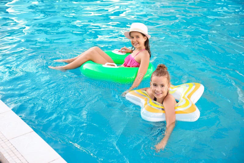 Fete fericite cu inele gonflabile în piscină stock image