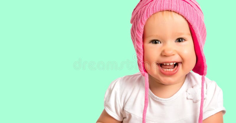 Fetiță veselă și veselă, într-o iarnă roz, tricotată cu pălărie zâmbitoare stock photos