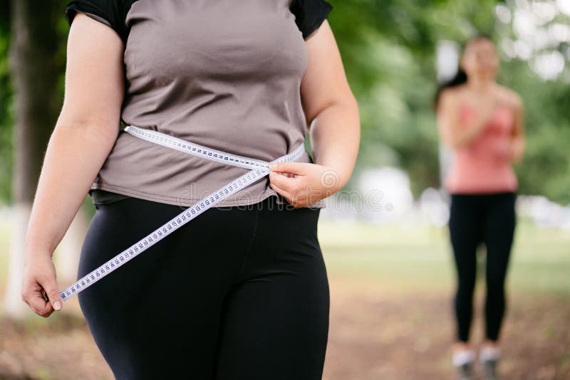 Fette Frau, die ihre Taille misst lizenzfreies stockfoto Fette Frau, die ihre Taille misst lizenzfreies stockfoto