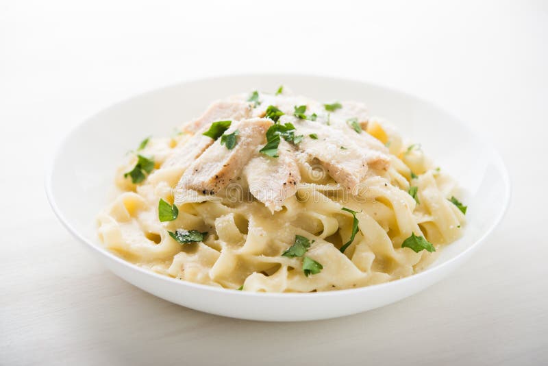 Fettuccine alfredo макаронных изделий с цыпленком, пармезаном и петрушкой на белом конце предпосылки вверх стоковые фото