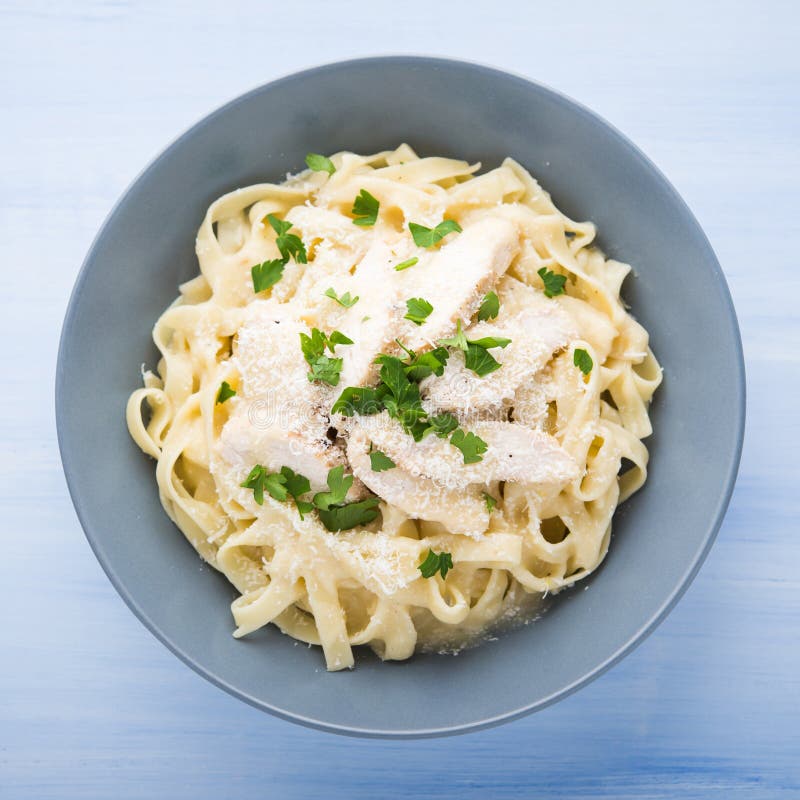 Fettuccine alfredo макаронных изделий с цыпленком, пармезаном и петрушкой на голубом деревянном взгляд сверху предпосылки стоковое фото Fettuccine alfredo макаронных изделий с цыпленком, пармезаном и петрушкой на голубом деревянном взгляд сверху предпосылки стоковое фото