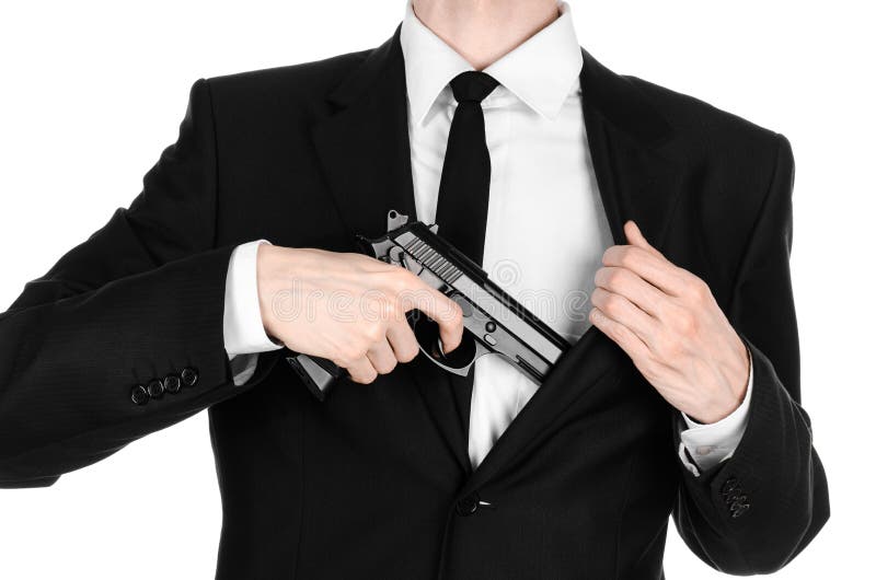 Feuerwaffen und Sicherheitsthema: ein Mann in einem schwarzen Anzug, der ein Gewehr auf einem weißen Hintergrund im Studio hält