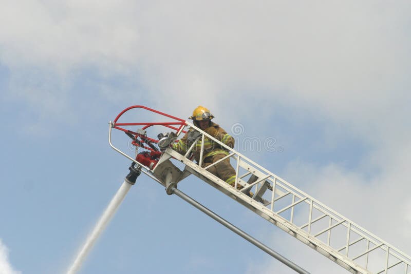 A firefighter on a ladder works to help control a fire at business. A firefighter on a ladder works to help control a fire at business.