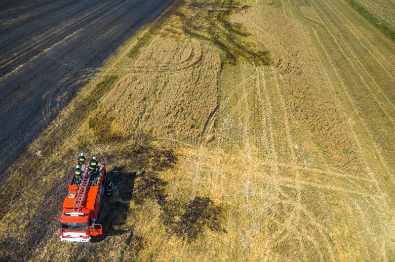 Feuerwehrmann-LKW, der an dem Feld auf Feuer arbeitet lizenzfreies stockbild Feuerwehrmann-LKW, der an dem Feld auf Feuer arbeitet lizenzfreies stockbild
