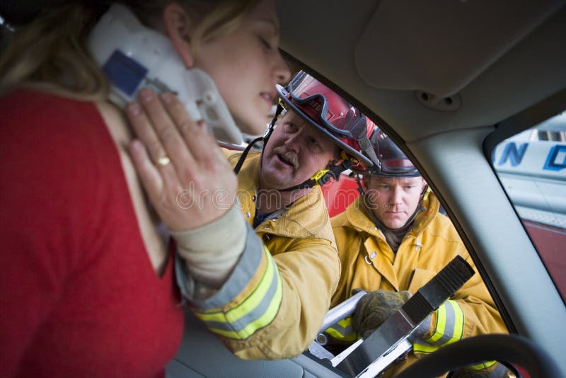 Firefighters helping an injured woman in a car. Firefighters helping an injured woman in a car.