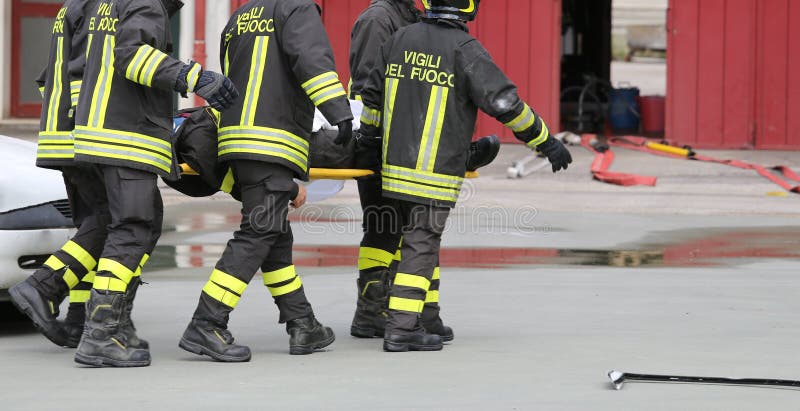 Feuerwehrmänner trugen verletzt weg auf Bahren stockbild Feuerwehrmänner trugen verletzt weg auf Bahren stockbild