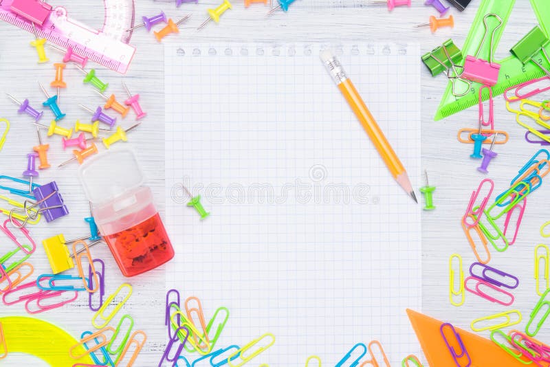 Feuille vide de bloc-notes, entourée par les fournitures de bureau colorées, les trombones et les boutons photo libre de droits Feuille vide de bloc-notes, entourée par les fournitures de bureau colorées, les trombones et les boutons photo libre de droits