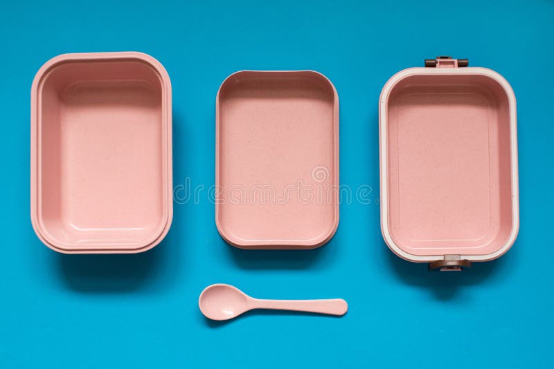 Fiambrera rosada vacía del bento con la cuchara en fondo azul foto de archivo Fiambrera rosada vacía del bento con la cuchara en fondo azul foto de archivo