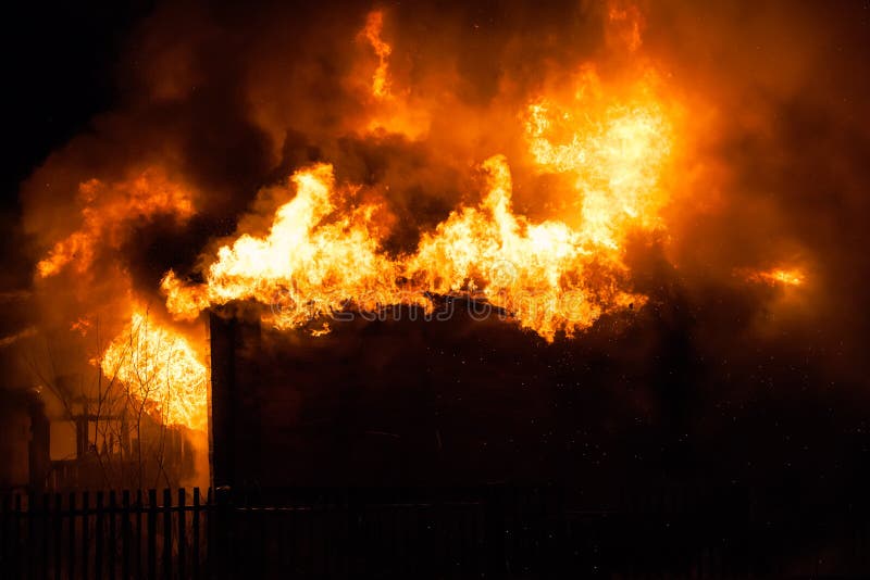 Arson or nature disaster - burning fire flame on wooden house roof. Arson or nature disaster - burning fire flame on wooden house roof