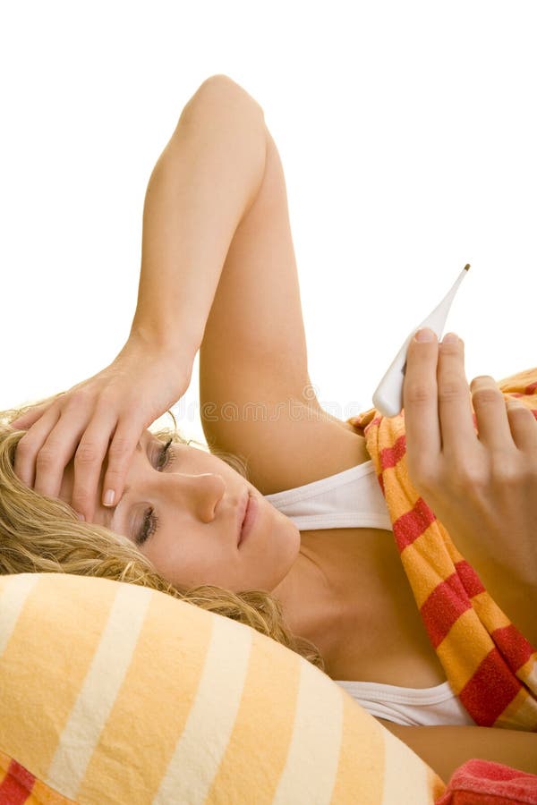 Blonde woman lying in bed and looking at a clinical thermometer. Blonde woman lying in bed and looking at a clinical thermometer