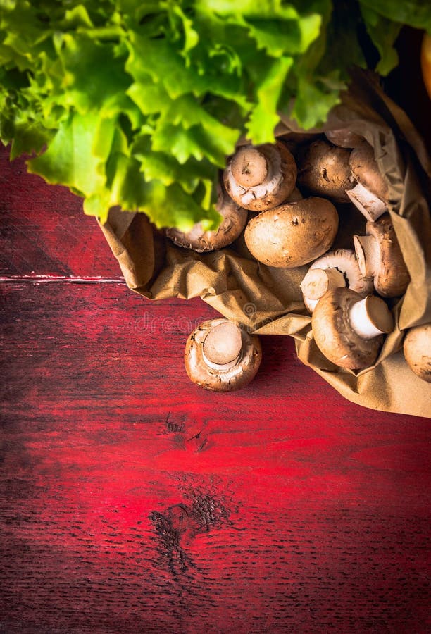 Field mushroom in paper bag on red wooden background