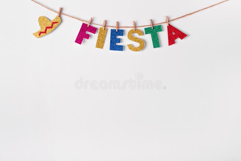 Fiesta word on pins against white wall background. Fragment of festive DIY decoration of interior. Cinco de mayo celebration.