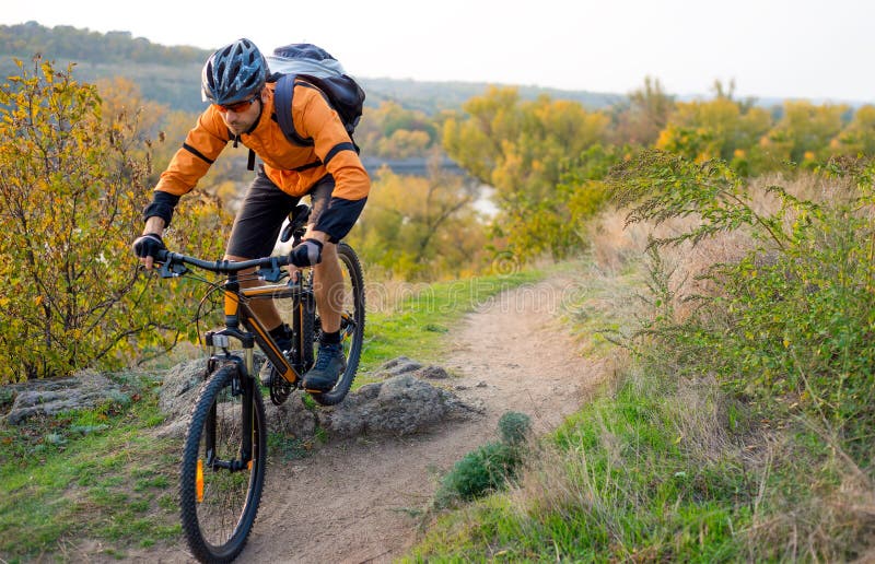 Fietser in Sinaasappel die de Bergfiets berijden op Autumn Rocky Trail Extreme Sport en het Concept van Enduro Biking royalty-vrije stock fotografie Fietser in Sinaasappel die de Bergfiets berijden op Autumn Rocky Trail Extreme Sport en het Concept van Enduro Biking royalty-vrije stock fotografie