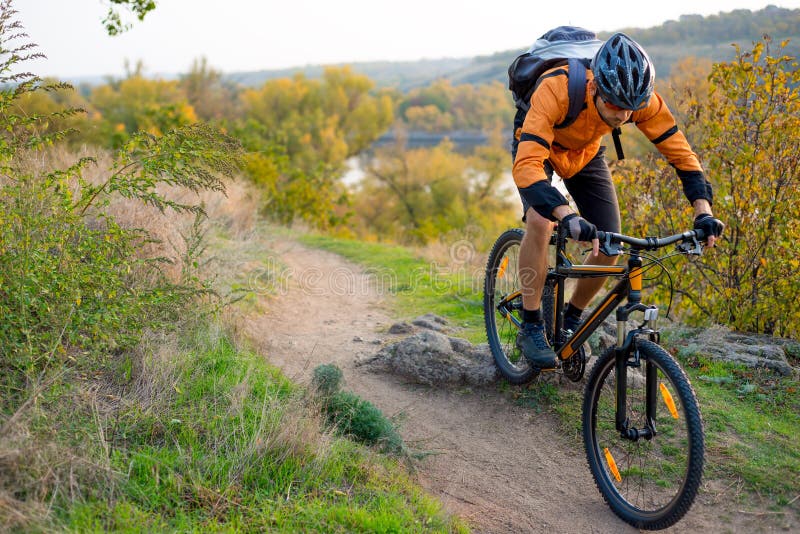 Fietser in Sinaasappel die de Bergfiets berijden op Autumn Rocky Trail Extreme Sport en het Concept van Enduro Biking royalty-vrije stock fotografie Fietser in Sinaasappel die de Bergfiets berijden op Autumn Rocky Trail Extreme Sport en het Concept van Enduro Biking royalty-vrije stock fotografie