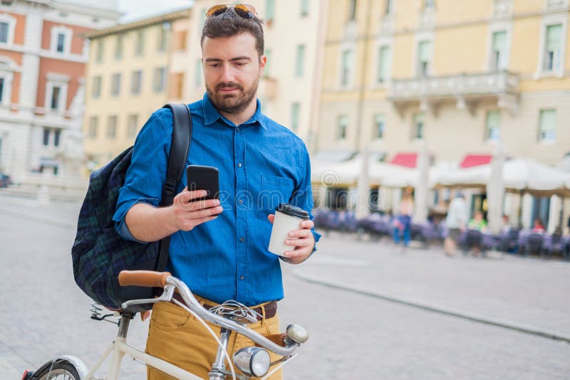Fietsermens die mobiele telefoon buiten het wachten op een fiets met behulp van stock fotografie Fietsermens die mobiele telefoon buiten het wachten op een fiets met behulp van stock fotografie