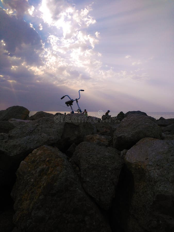 Fietsvisser die aan visserij op de achtergrond van een mooie zonsondergang kwam royalty-vrije stock afbeelding Fietsvisser die aan visserij op de achtergrond van een mooie zonsondergang kwam royalty-vrije stock afbeelding