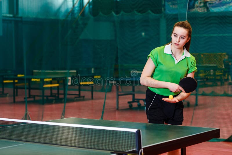 Fifteen year old beautiful Caucasian teen girl in green sports t-shirt makes a serve in table tennis stock photos Fifteen year old beautiful Caucasian teen girl in green sports t-shirt makes a serve in table tennis stock photos