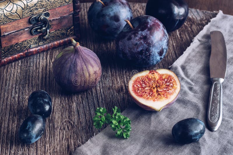 The fig is cut on a wooden table with grapes and plums. Still life with figs. Selective focus