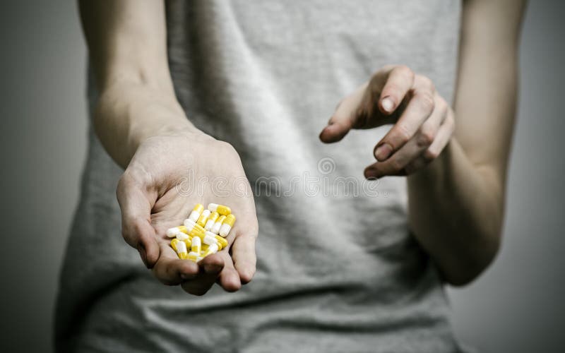 The fight against drugs and drug addiction topic: addict holding a narcotic pills on a dark background