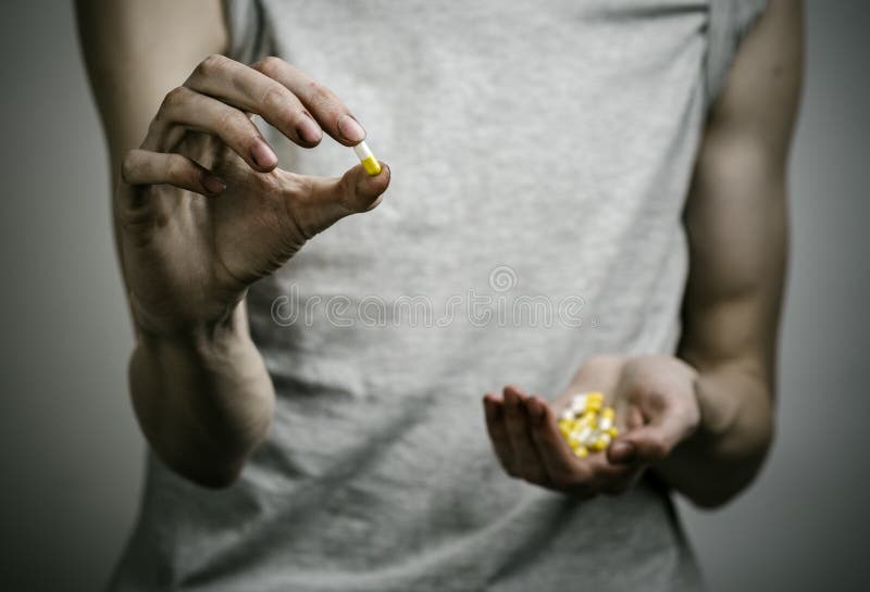 The fight against drugs and drug addiction topic: addict holding a narcotic pills on a dark background