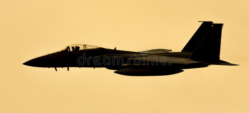 Fighter jet aircraft isolated silhouette at sunset with golden light.  USAF F15 American airforce.