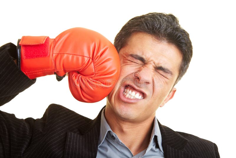 Business man hitting himself with a red boxing glove in the face. Business man hitting himself with a red boxing glove in the face