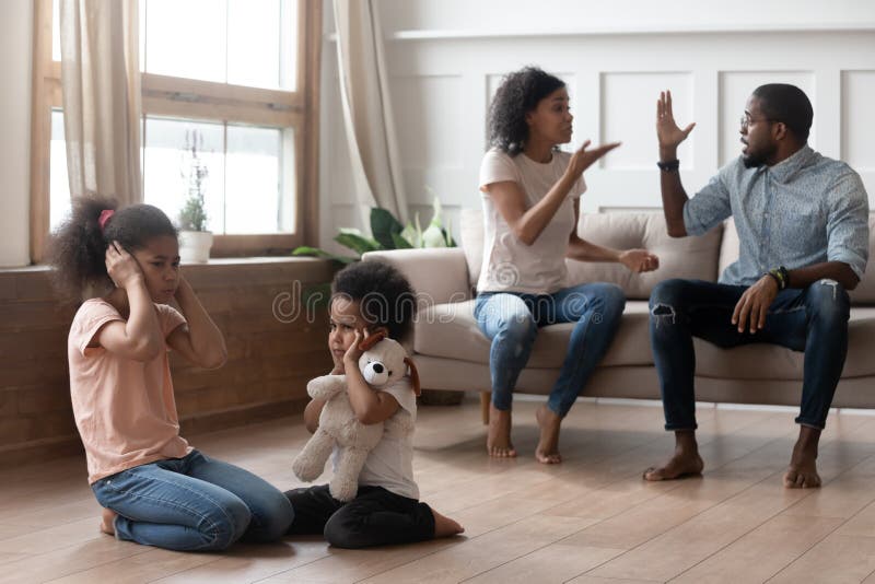 African american angry married couple arguing and shouting, while two mixed race upset stressed kids sitting on floor, closing ears hurt by parents fighting, family conflicts, divorce concept. African american angry married couple arguing and shouting, while two mixed race upset stressed kids sitting on floor, closing ears hurt by parents fighting, family conflicts, divorce concept.