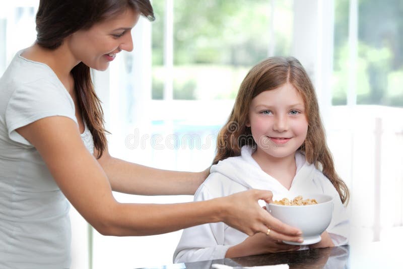 Figlia d'alimentazione della mamma cereale da prima colazione immagine stock Figlia d'alimentazione della mamma cereale da prima colazione immagine stock
