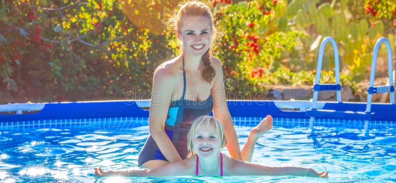 Figlia d'istruzione della madre attiva felice da nuotare nella piscina fotografie stock Figlia d'istruzione della madre attiva felice da nuotare nella piscina fotografie stock