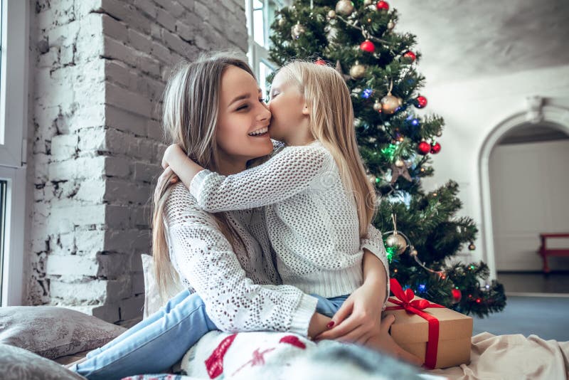 Figlia felice che bacia sua madre sopra il fondo delle luci dell'albero di Natale immagini stock libere da diritti Figlia felice che bacia sua madre sopra il fondo delle luci dell'albero di Natale immagini stock libere da diritti