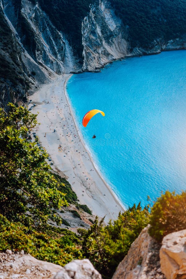 Figura de un skydiver del paracaidista con el paracaídas anaranjado contra una laguna azul de la playa de Myrtos, isla de Kefalon foto de archivo Figura de un skydiver del paracaidista con el paracaídas anaranjado contra una laguna azul de la playa de Myrtos, isla de Kefalon foto de archivo