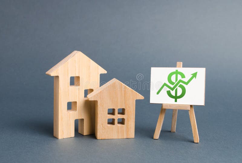 Figuras de madeira das casas e um cartaz com seta verde acima O conceito do crescimento do valor de bens imobili?rios Liquidez do foto de stock Figuras de madeira das casas e um cartaz com seta verde acima O conceito do crescimento do valor de bens imobili?rios Liquidez do foto de stock