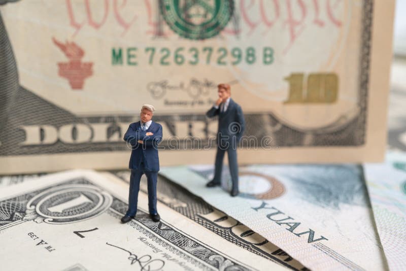 Figure businessman standing on US dollar and YUAN banknote and thinking. Concept of trading war royalty free stock photo Figure businessman standing on US dollar and YUAN banknote and thinking. Concept of trading war royalty free stock photo