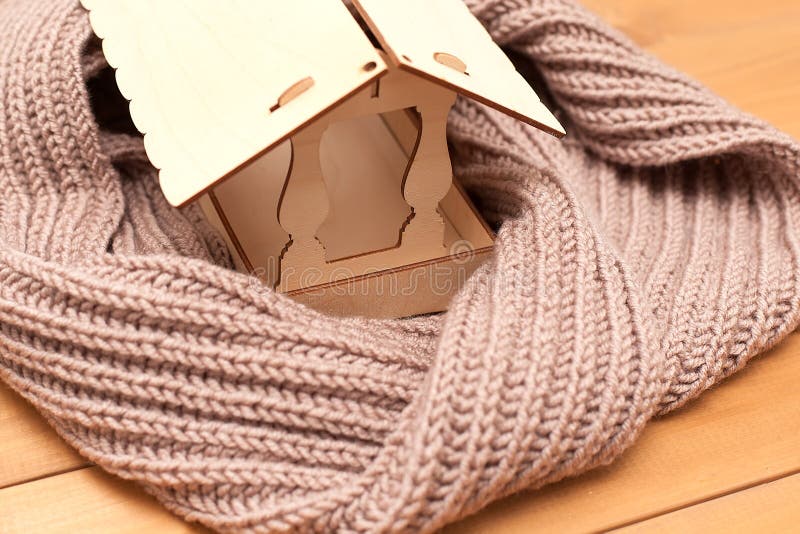 Figure of house and warm scarf on light background. Concept of heating season. royalty free stock image