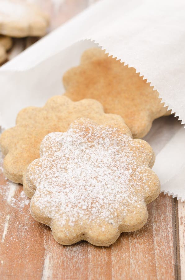 Figured cookies sprinkled with powdered sugar in a paper bag
