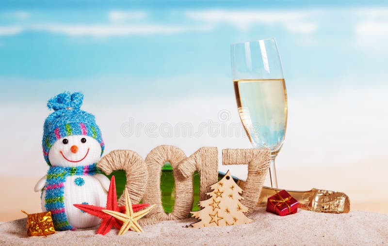 Figures 2017, bottle champagne, glass, snowman, tree, starfish against sea.