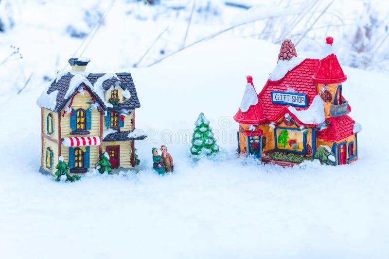 The figures of people standing in the snow between the two houses and a small New Year tree. royalty free stock image The figures of people standing in the snow between the two houses and a small New Year tree. royalty free stock image