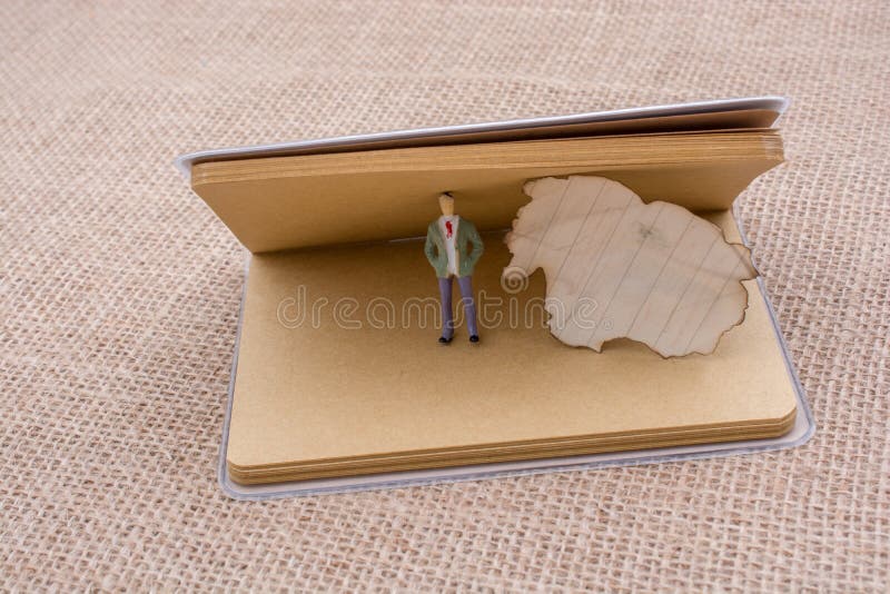 Figurina con una carta bruciata su un taccuino immagini stock