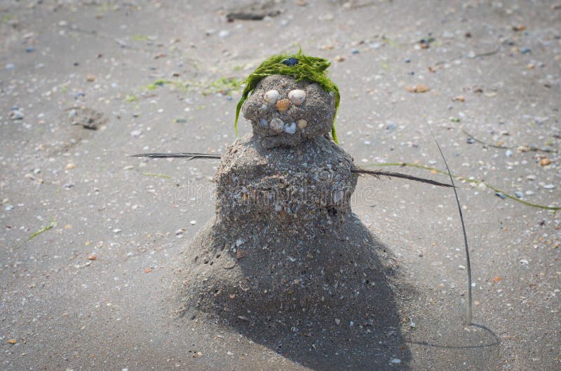 Figurine of a Snowman Out of Sand, Shells and Seaweed on the Beach