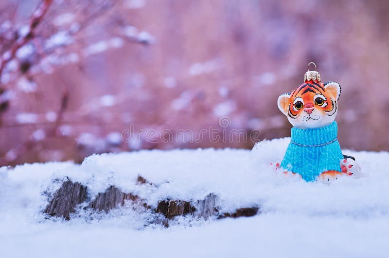 Figurine of tiger, wooden fir trees in snow on beige background. Tiger symbol of the Chinese new year 2022