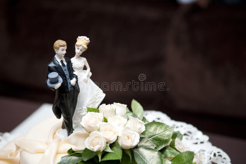 Figurines of the bride and groom at the top of the wedding cake, close-up. copy space