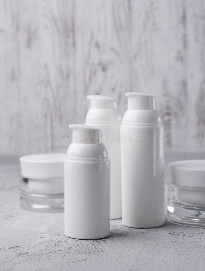 Fije de botellas poner crema cosméticas en fondo gris foto de archivo libre de regalías Fije de botellas poner crema cosméticas en fondo gris foto de archivo libre de regalías