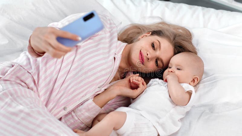 Fijne jonge moeder en kleine baby die een zelfgemaakte smartphone gebruikt Middelgrote opname op RED-camera