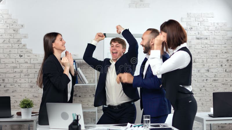 Fijne zakenmensen die een succesvolle deal vieren dansen klappende hand die plezier heeft in modern kantoor